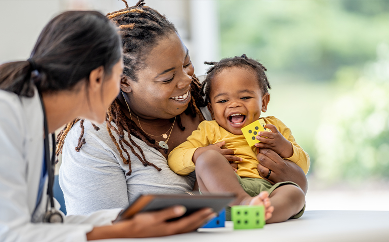 woman doctor looking at woman laughing and holding laughing baby